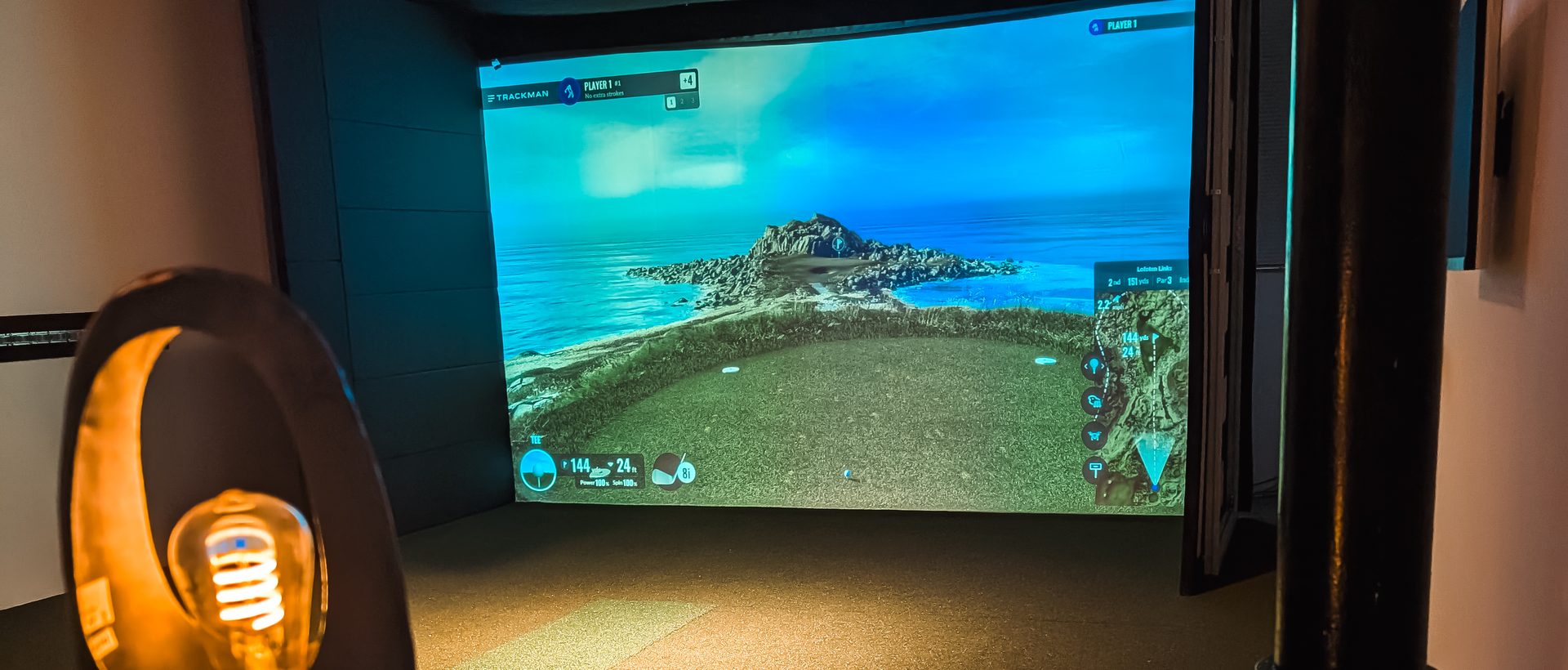 Privater Simulator-Raum bei Birdies mit Küsten-Golfplatz auf der Leinwand