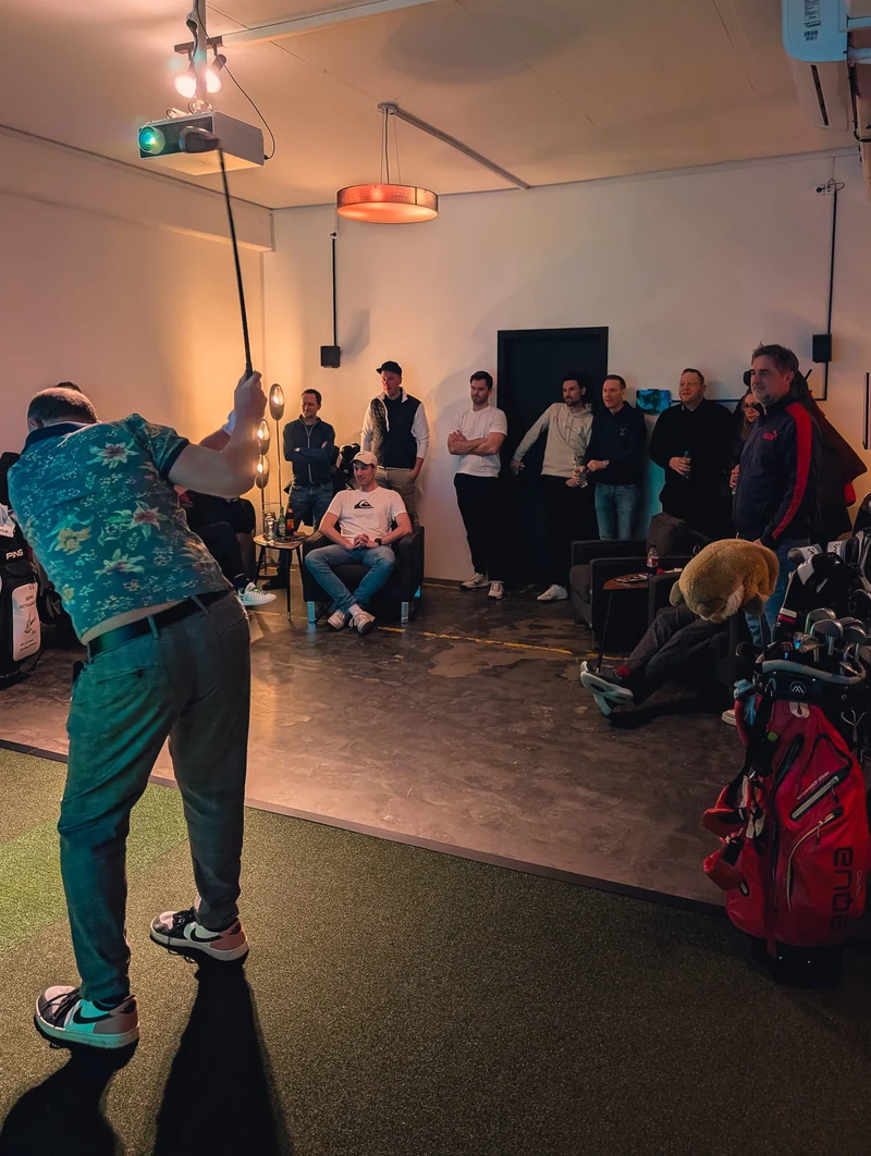 Firmenevent bei Birdies: Abschlag am Simulator, die Kollegen schauen aus der Lounge zu