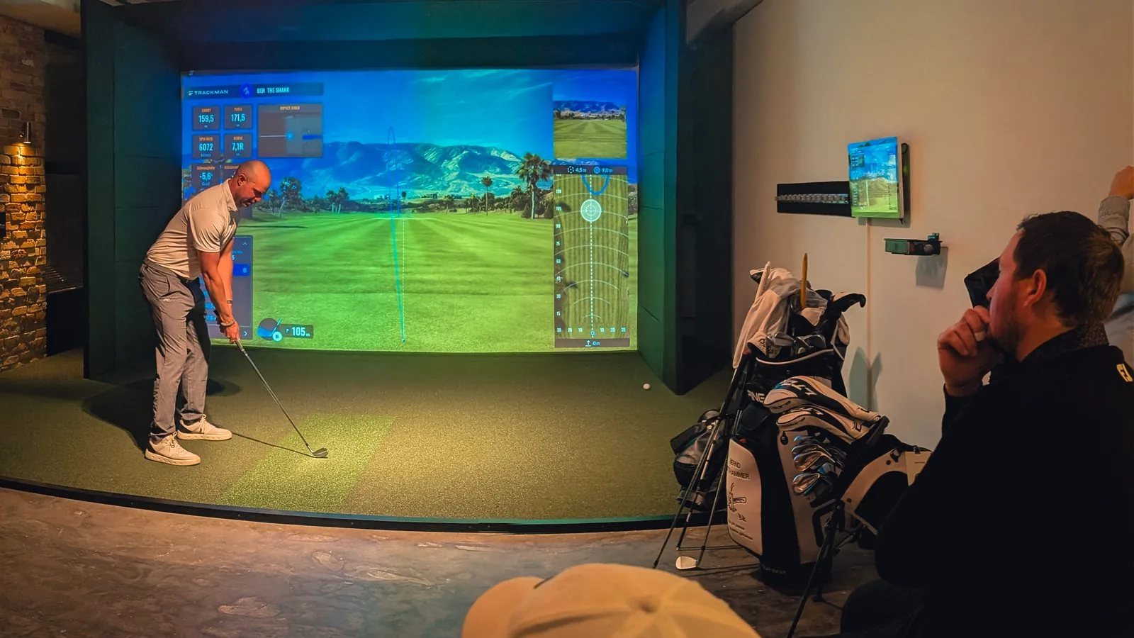 Blick auf den Trackman-Simulator bei Birdies: ein Spieler schl&auml;gt ab, die Gruppe verfolgt Schl&auml;gerdaten und Ballflug auf der Leinwand