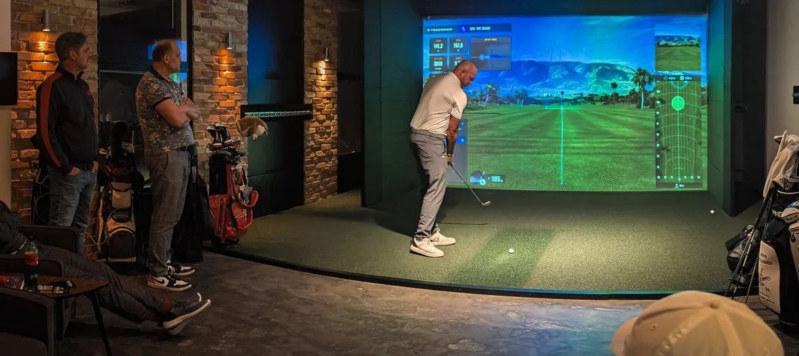 Simulator-Raum bei Birdies: ein Spieler schlägt vor der Trackman-Leinwand ab