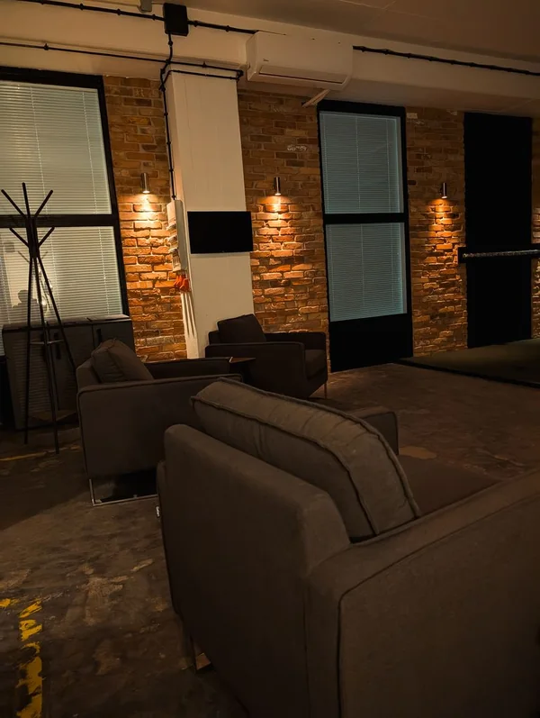 Lounge mit Sesseln vor der Backsteinwand