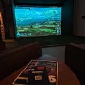 Leerer Simulator-Raum bei Birdies, auf der Leinwand ein Bergpanorama